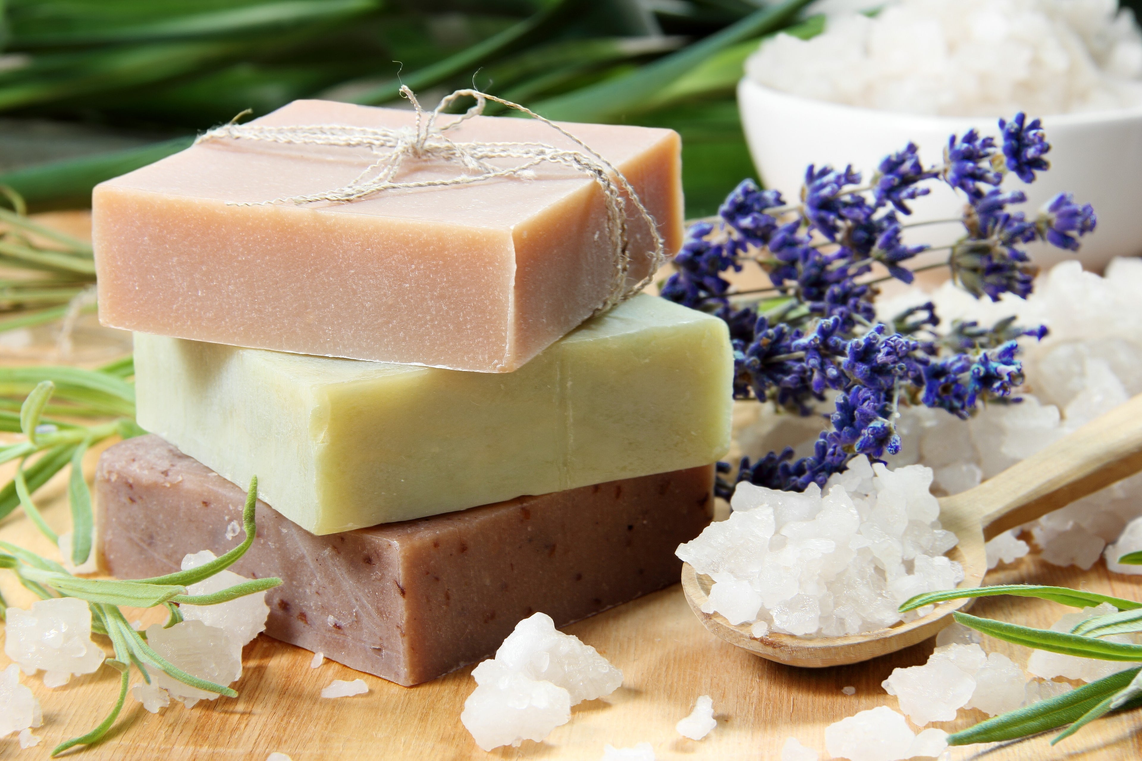 Stack of soap bars with lavender and rosemary on a wooden surface