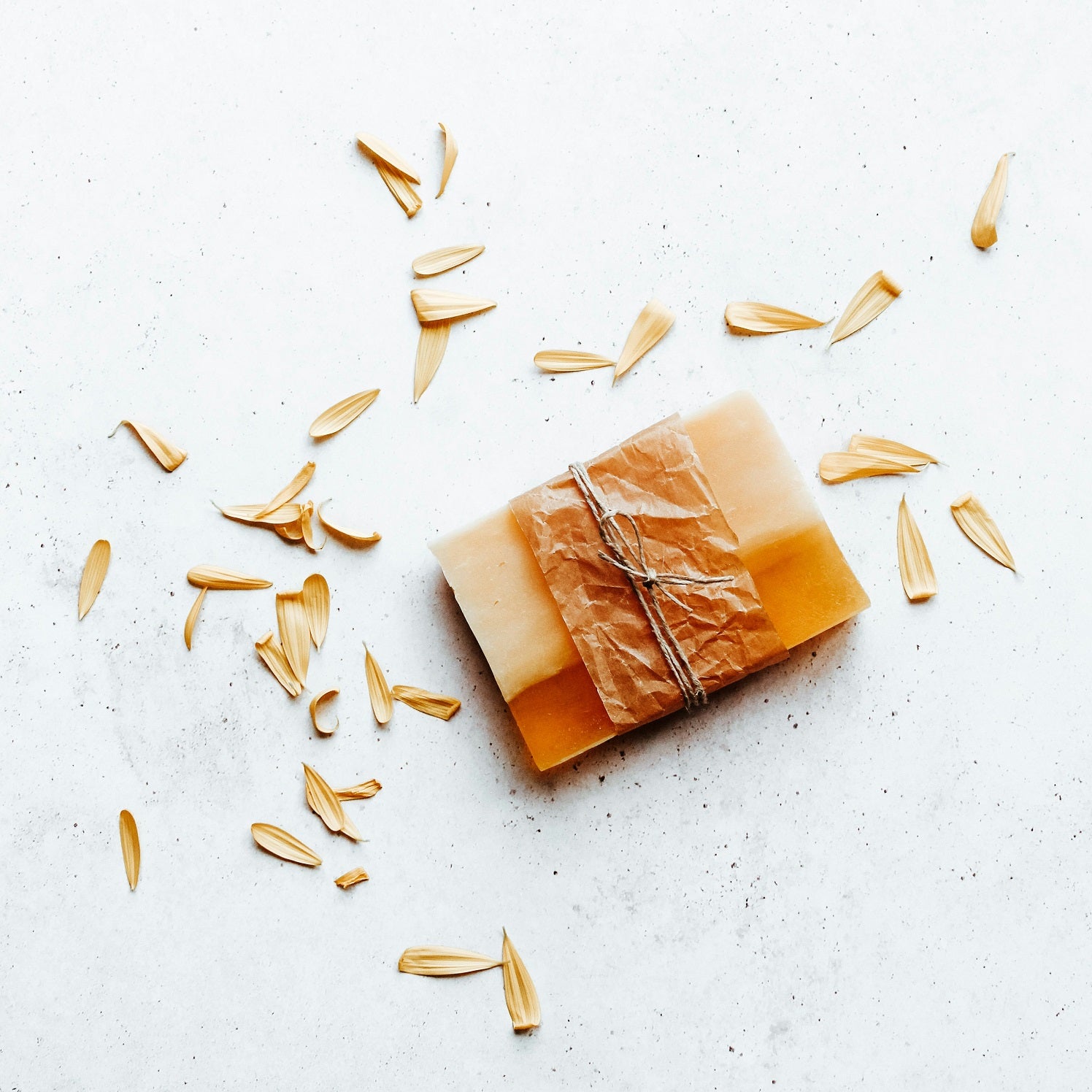 Bar of soap with a natural finish on a light surface with scattered dried leaves.